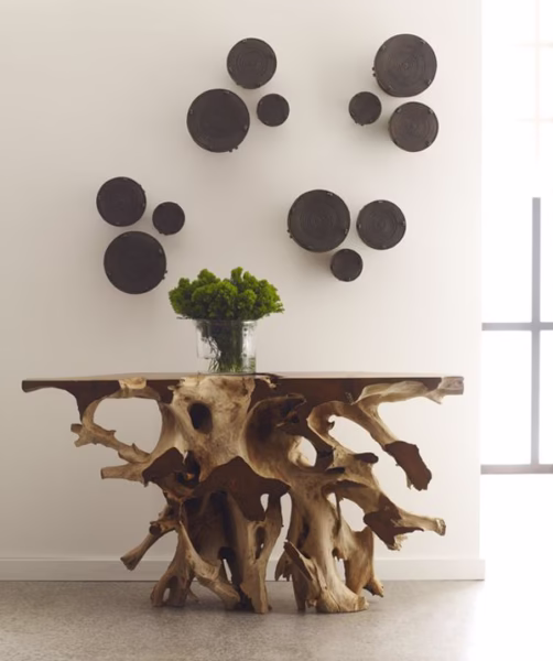 Tafel van boomwortels met een tafeldecoratie er op en tegen een witte muur met ronde wanddecoraties.